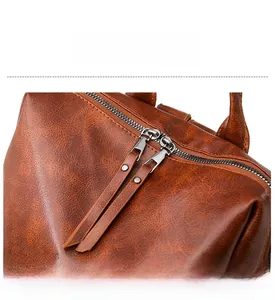 Detail of brown leather backpack featuring dual silver zippers with long leather pullers