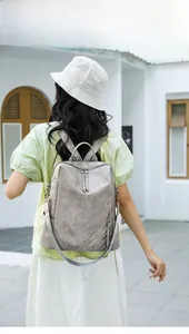 Rear view of a grey faux leather checkerboard backpack with zipper details on a model