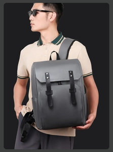 Detail view of dark grey faux leather backpack with black straps and silver rivets on model