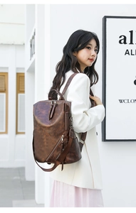 Detail of vintage brown PU leather backpack with diagonal zipper pocket and metal texture