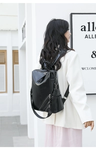 Detail view of the side zipper pocket and premium leather texture on a black backpack