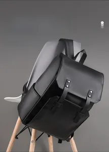 Detail of black leather backpack with silver rivets and buckle closure hanging on chair