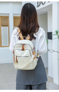Outdoor shot of cream geometric stitched backpack with brown leather details on model