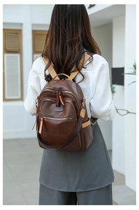 Outdoor shot of a vintage brown PU leather backpack with multi-zipper pockets and contrast straps