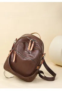 Detailed view of brown lychee grain leather backpack with dual zippers on beige stand