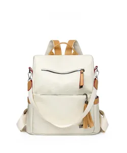 Detail view of cream leather backpack featuring fringe tassel and front zipper pocket