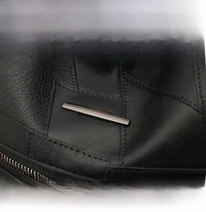Close-up of black pebble grain leather texture with premium metal hardware and zipper detail