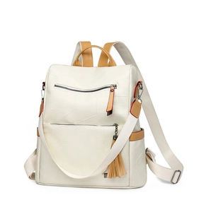 Close-up of white PU leather backpack featuring unique textured panels and brown tassel detail