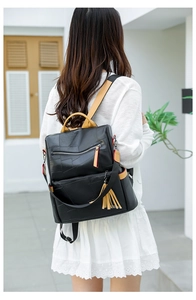 Close-up of black PU leather backpack featuring yellow handle and stylish tassel detail