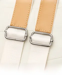 Detail of adjustable shoulder strap with silver buckle and white fabric on leather bag
