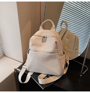 Close-up of off-white woven texture backpack with silver zippers and top handle details