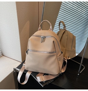 Detail view of stylish beige backpack with twill texture and dual zipper compartments