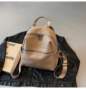 Detailed view of beige woven texture backpack placed on a black leather jacket