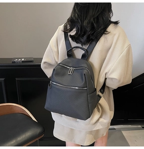 Detail of black backpack with twill texture and silver zippers on a model's back