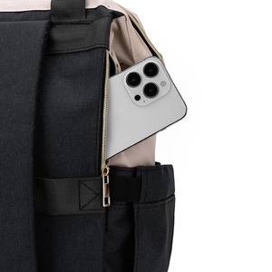 Détail d'une poche latérale zippée sur un sac à dos beige et noir avec un smartphone