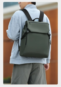Outdoor shot of matte dark green waterproof laptop backpack with flap cover and side buckles