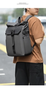 Detail of grey roll-top backpack with black buckle straps and water-resistant fabric