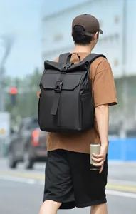 City street view of a black roll-top backpack with buckle closure for travel and commuting