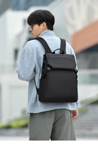 Close-up of man wearing black minimalist laptop backpack in urban outdoor city setting