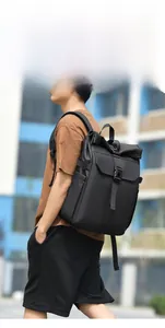 Side view of black roll-top backpack with buckle closure on a model in urban setting