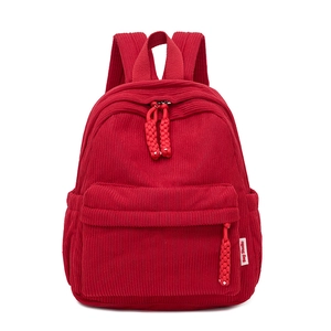 Kleine winterrugzak van rood corduroy met zakken en decoratieve geweven ritstrekkers