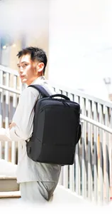 Waterproof black commuter backpack with external USB port shown on male model in city