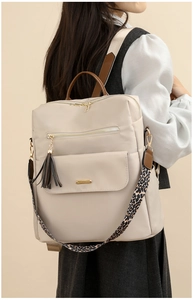 Detail of off-white travel backpack featuring brown leather accents and leopard print strap