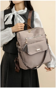 Close-up of taupe nylon backpack with leopard print strap and metallic zippers