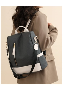 Detail view of woven grey backpack with white leather straps on a brown suit model