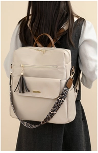 Detail of beige nylon backpack featuring leopard print strap and tassel charm