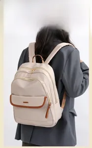 Back view of a beige nylon backpack featuring brown leather trim and multi-pocket layout