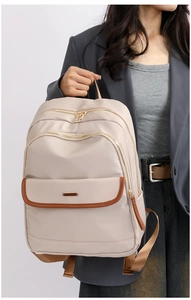 Detail of beige nylon backpack with brown leather trim and golden metal hardware accent