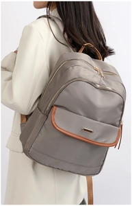 Detail of grey nylon travel backpack with brown leather trim and multi-pocket design