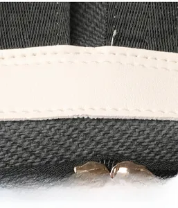 Detail of black woven fabric with off-white leather trim and gold metal zipper