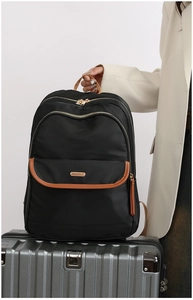 Detail of waterproof black nylon backpack with brown leather trim on silver suitcase