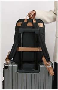 Rear view of black nylon travel backpack with luggage strap secured on a suitcase