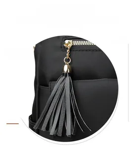 Detailed macro view of gold zipper and black leather fringe tassel on nylon backpack