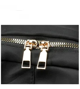 Detail of smooth gold double metal zippers on black durable nylon backpack fabric