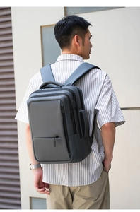 Side view of dark gray nylon backpack shown on model during commute or travel
