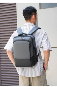 Detail of ergonomic padded shoulder straps and side handle on a grey business backpack
