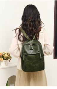 Détail d'un sac à dos en cuir vert foncé montrant la poche latérale et les boucles dorées