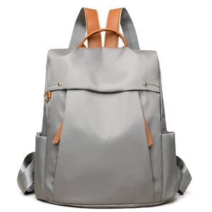 Minimalist grey nylon backpack for women with brown leather handles and gold-tone hardware