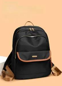 Close-up of black nylon backpack with brown leather trim and gold hardware details