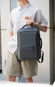 Detailed side view of dark grey waterproof fabric backpack held by hand for business commute