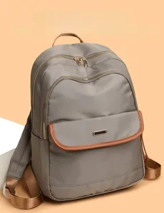 Detail view of water-resistant gray nylon backpack with brown leather trim and zipper pockets