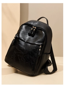 Détail du sac à dos en similicuir noir avec boucles dorées sur un support minimaliste