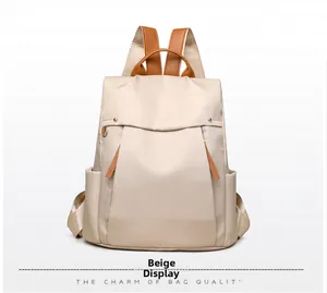 Detail view of beige canvas backpack featuring brown leather handles and sturdy straps