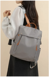 Close-up of gray canvas backpack with brown leather trim showing side pocket detail