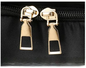 Close-up of golden metal zippers on a black canvas laptop backpack detail
