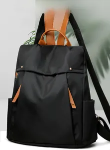Detail of waterproof black canvas backpack featuring brown leather trim and metal buckles